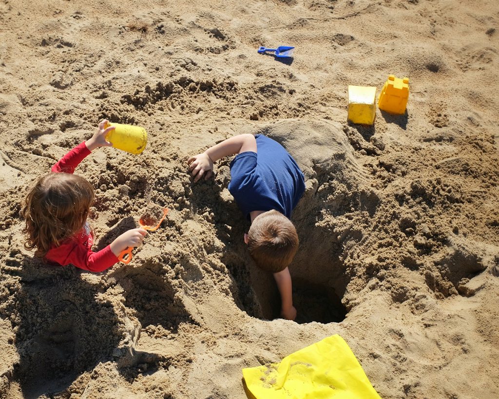 niños haciendo hoyos en la arena de gandia